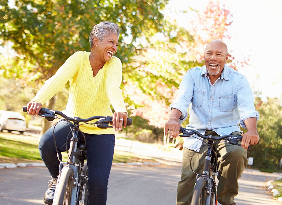 Medicare - Cheerful Senior Couple Having Fun Riding Their Bikes in a Park on a Beautiful Sunny Day