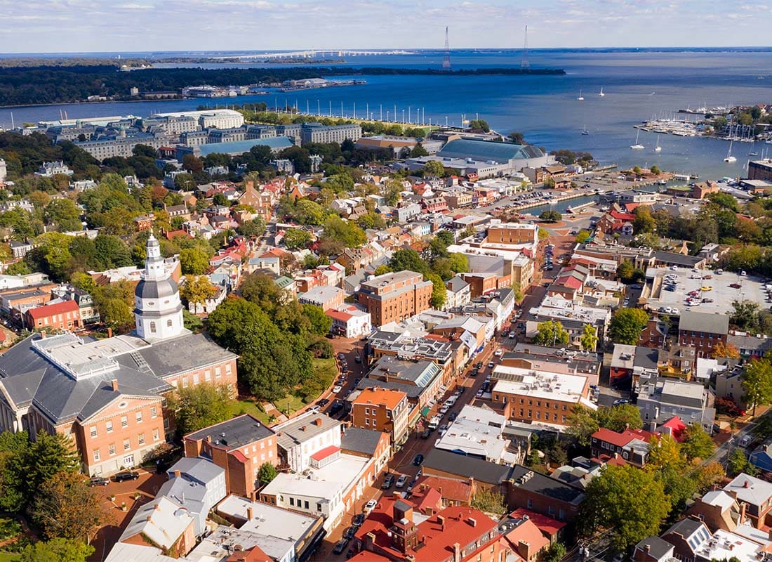 Our History - Aerial View of Buildings and Homes in Downtown Annapolis Maryland Surrounded by Green FOliage with the Coast Visible in the Background