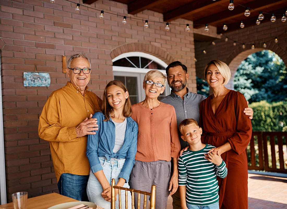 Personal Insurance - Portrait of a Cheerful Extended Family with Two Children and Grandparents Standing on the Back Patio of Their Home